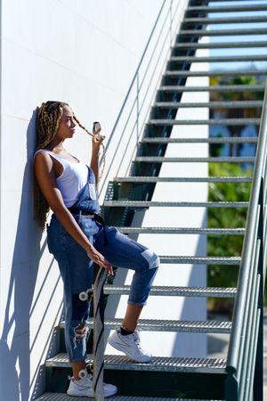 Side of woman playing with hair on stairs with skateboard