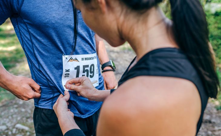 Trail athlete placing race number to her partner