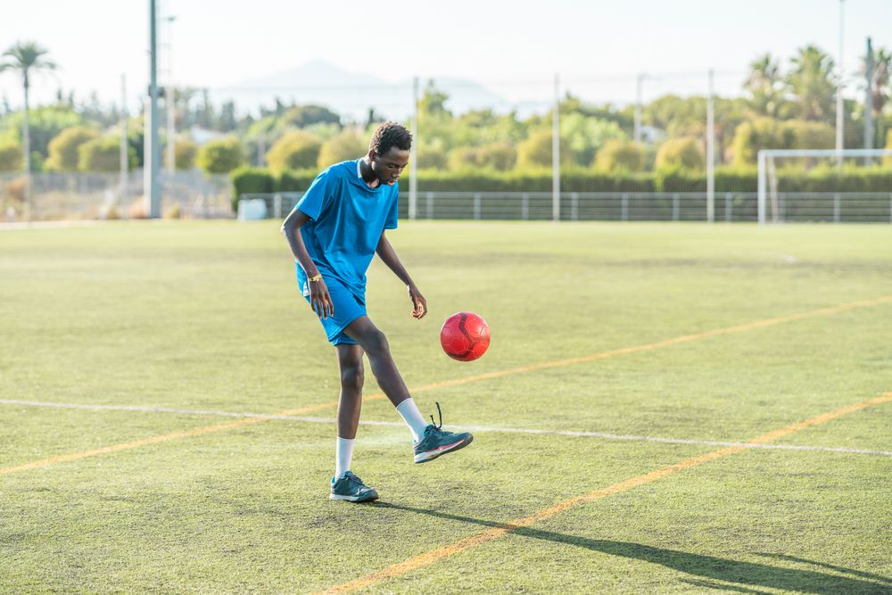 Black teenager juggling football ball