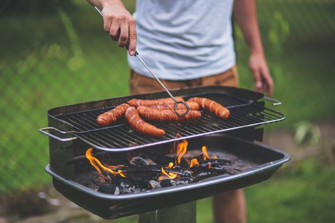 Cropped image of a man barbequing sausages outdoor