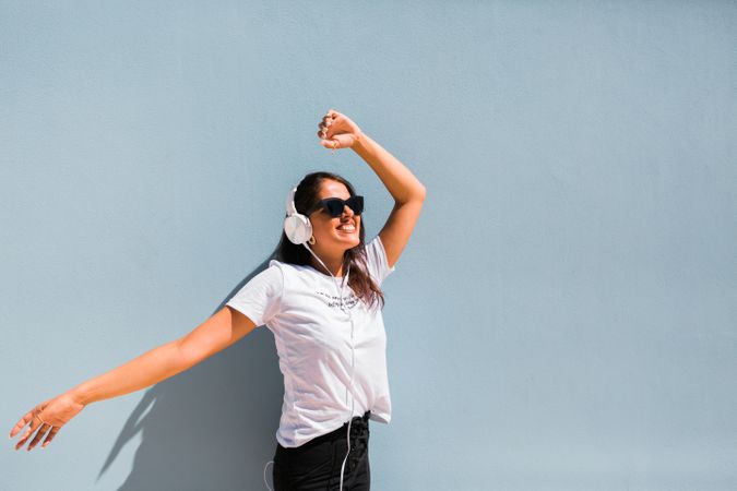Cheerful casual woman in sunglasses standing on city street