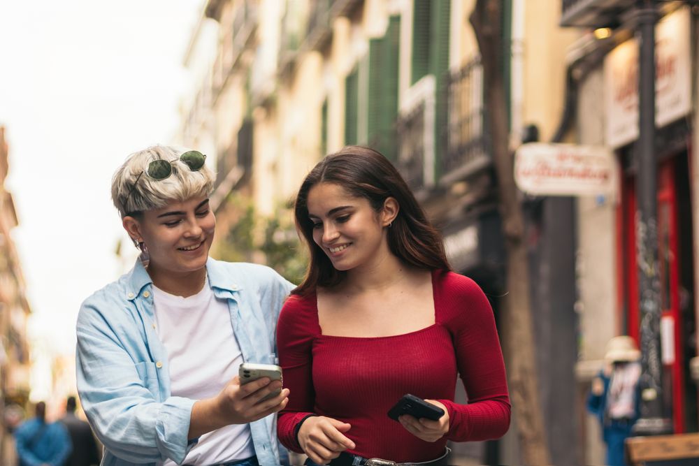 two women walking and watching something her mobiles