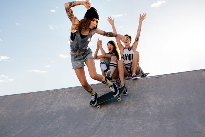Female skateboarding at skate park with friends cheering