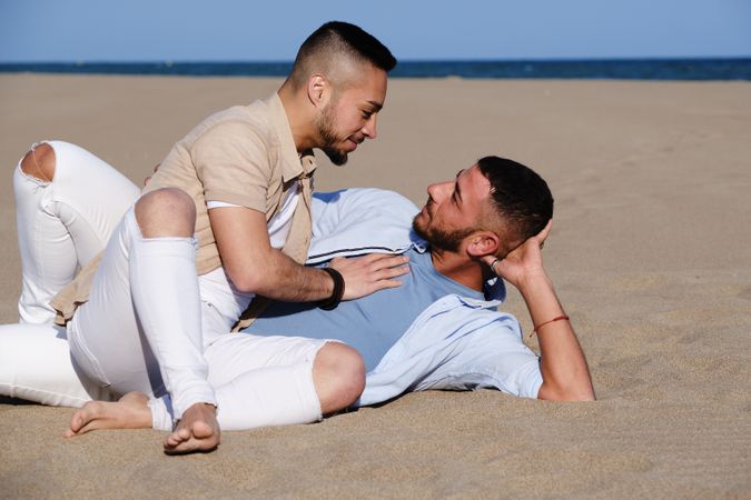 Affectionate gay couple relaxing on beach
