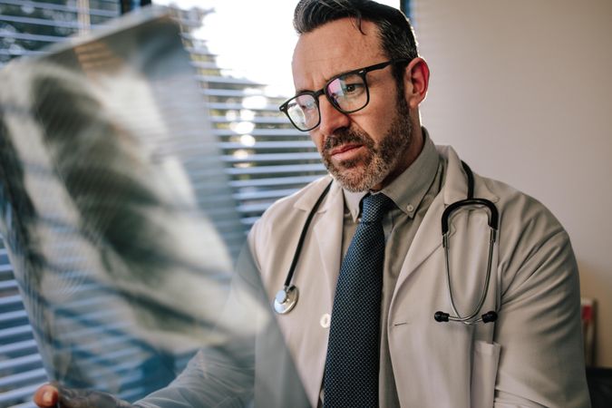Concerned male doctor looking at chest x ray in his office