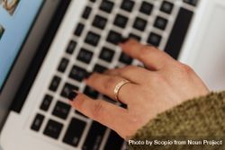 Cropped image of a hand wearing golden ring using computer 0LXay0
