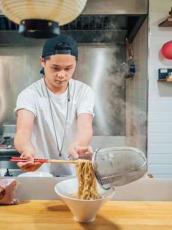 Asian male cooking ramen in cafe