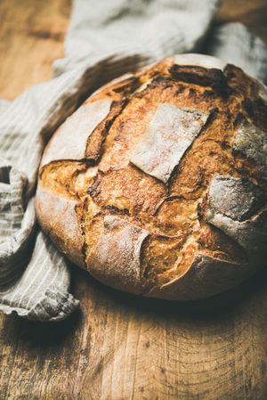 Close up of scoring on homemade loaf of bread on bread board