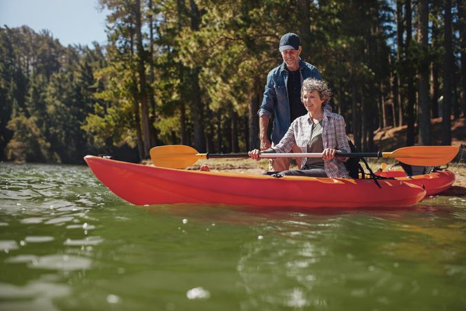 Portrait of mature man giving instruction to woman paddling a kayak in the lake