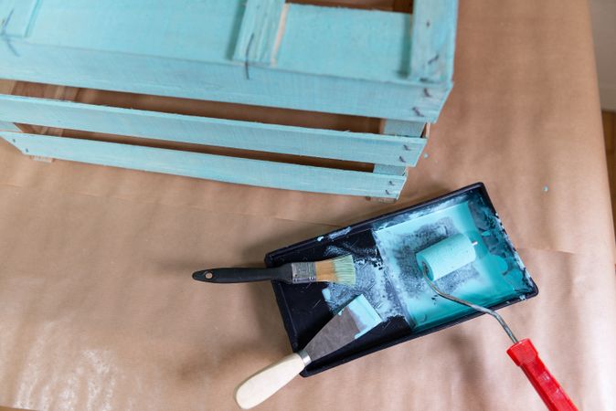 Freshly painted wooden box and paint tray on table