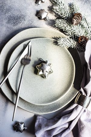 Silver table setting for Christmas dinner with star ornament and branch