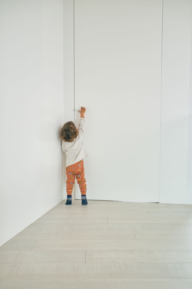 Unrecognizable toddler reaching for doorknob at home