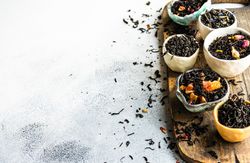 Bowls of loose leaf tea on board with copy space