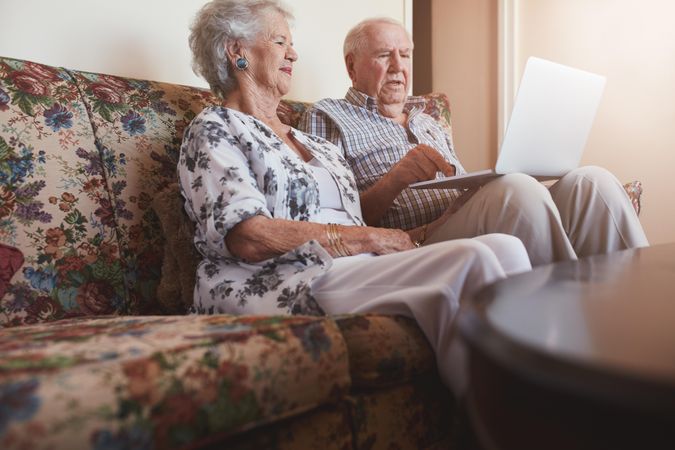 Mature man and woman relaxing on a sofa using laptop