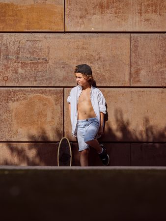 Stylish preteen skater standing outside building