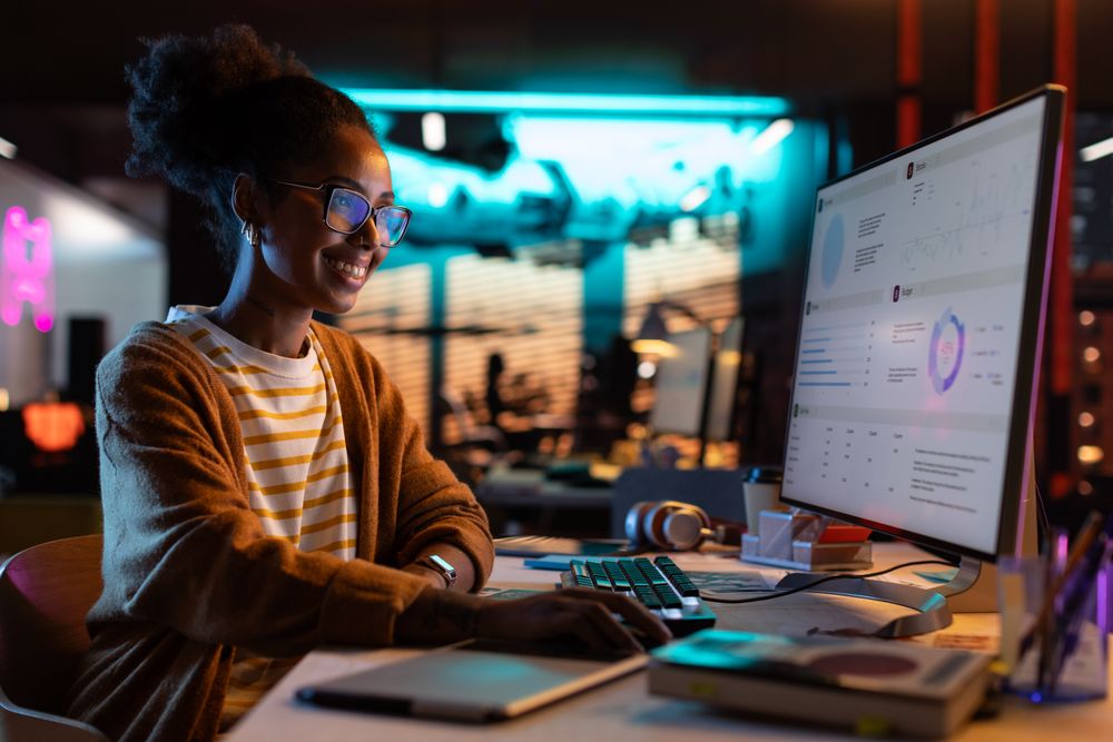 Portrait of a Happy Successful Black Businesswoman Using Desktop Computer in Creative Agency in the Evening.