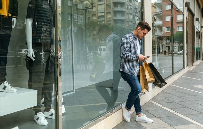 Young man with shopping bags and mobile