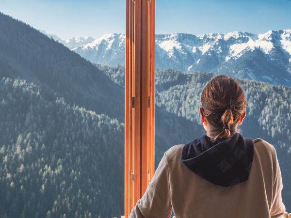 Anonymous woman looking at mountains from window