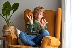 Focused boy wrapping colourful string around fingers