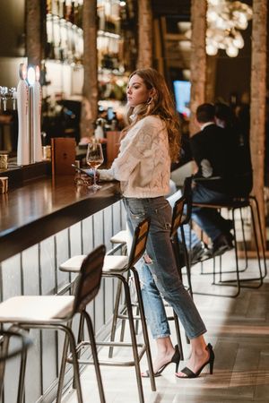 Stylish woman drinking wine in bar