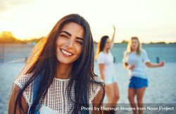 Portrait of brunette woman with friends in background on beach 5Xqzv4