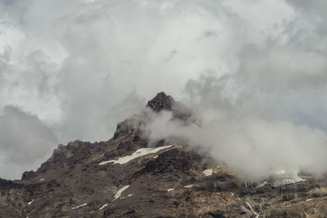 Harsh mountain snowy peak shrouded in fog
