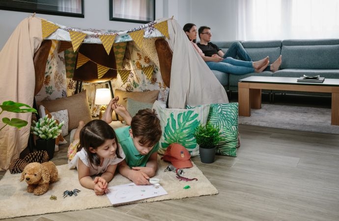 Children playing camping at home while their parents watch TV
