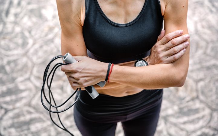 Woman with crossed arms posing with skipping rope in a park