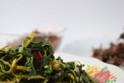 Plate of cooked greens side dish on table with space for text