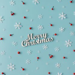 Christmas pattern made of snowflakes and red berries with “Merry Christmas” on blue background