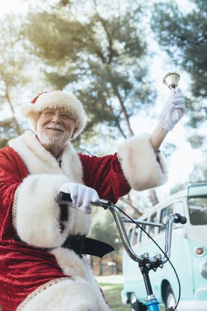 Happy Santa Claus riding bicycle by van
