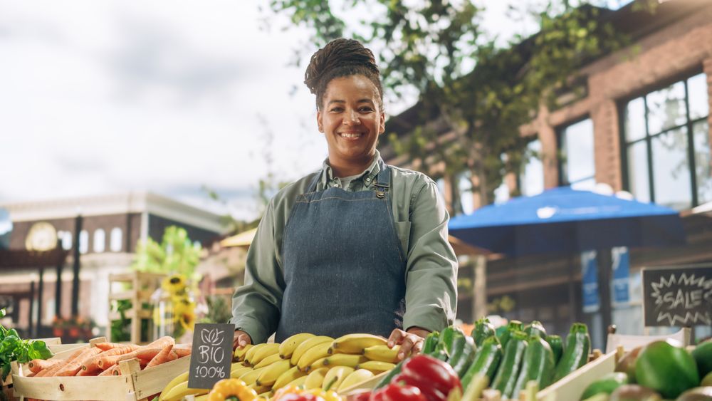 Portrait of a Black Female Working at a Farmers Market Stall with Fresh Organic Agricultural Products.