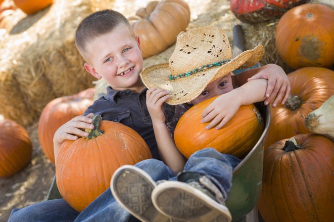 Two Little Boys Playing in Wheelbarrow at the Pumpkin Patch