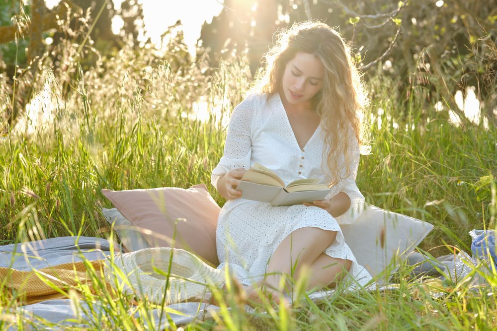 Content woman reading book on grassy meadow
