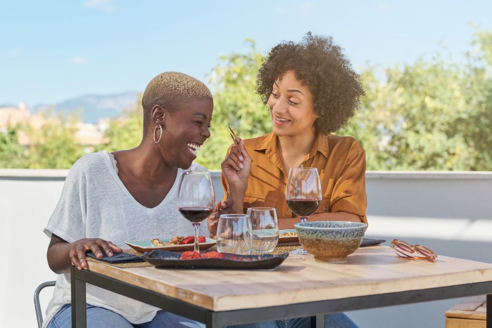 Laughing diverse women having lunch on terrace