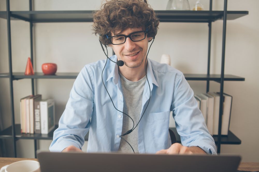 Male agent talking on head set in front of laptop on desk