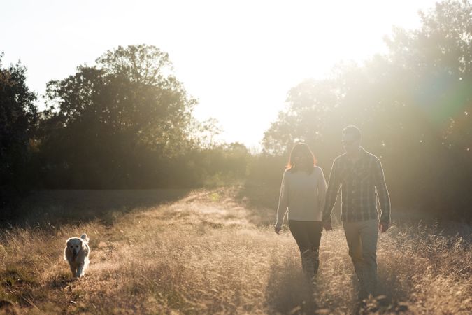 Couple with dog in countryside at sunset