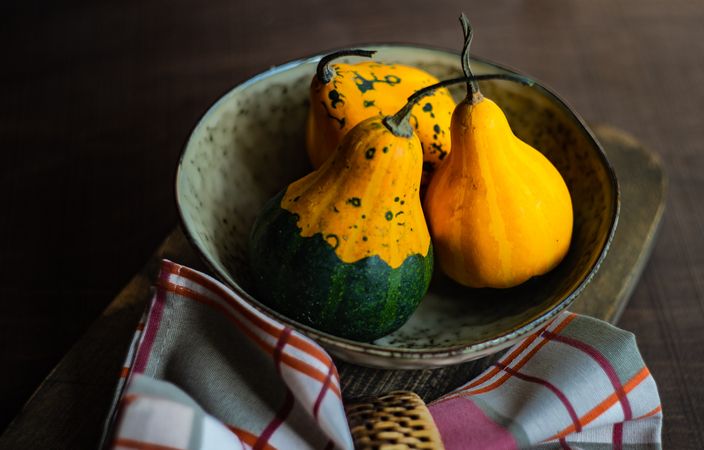 Rustic bowl with three squashes and kitchen towel