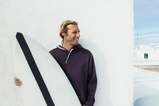 Smiling man standing with surf board