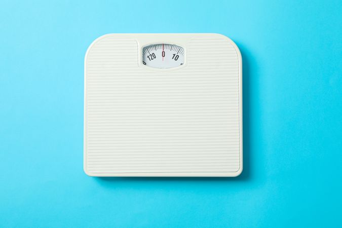 weigh scales on blue background, top view