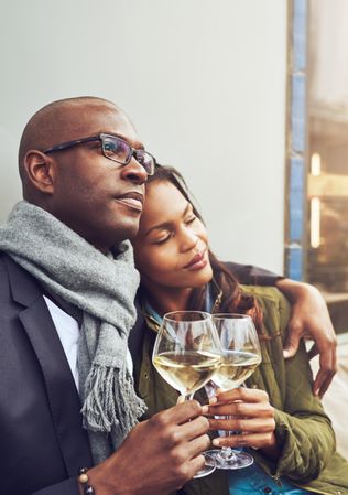 Black couple in each others arms while dining alfresco with wine in hand