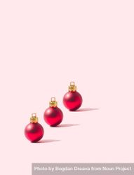 Three red round ornaments on a pink background 4ZkE9b