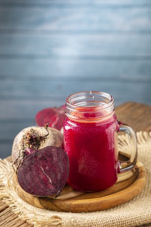 Red beet juice in a glass cup on the wooden table.