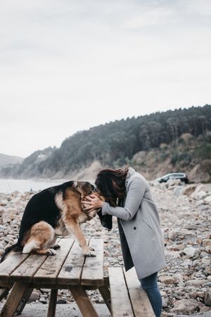 Young woman hugging sad dog on seashore