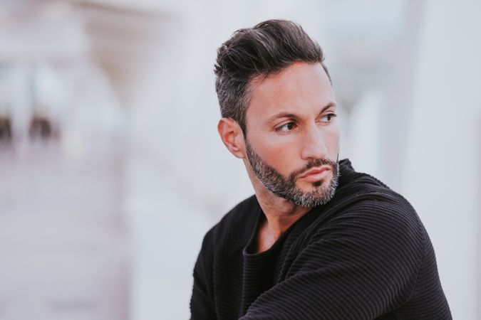 Adult stylish smiling man near grey wall on street