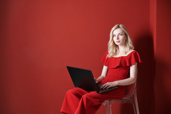 Young adult woman sitting on a chair and working on laptop