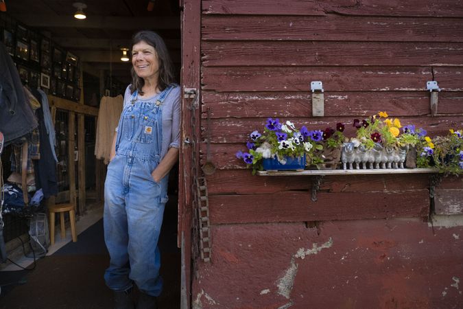 Happy woman farmer standing in the doorway of her animal stable