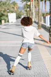 Back of woman on roller skates along a road with palm trees