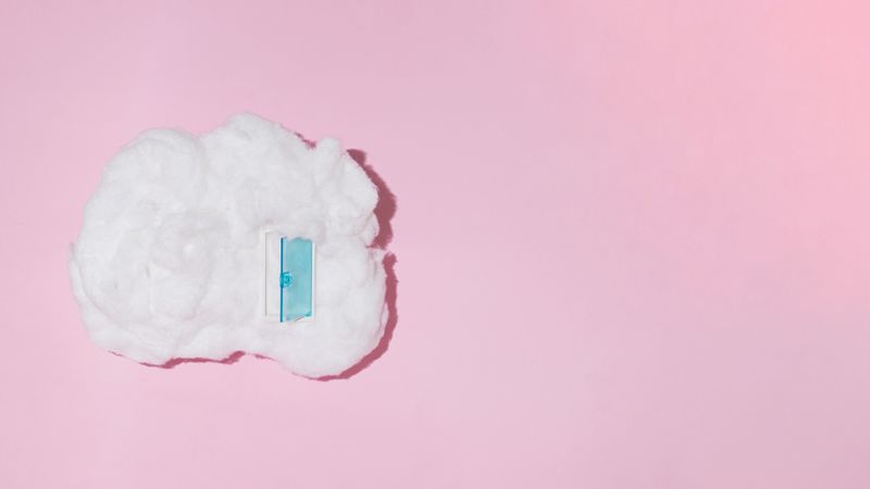 Single cotton cloud with blue door on pink background with copy space