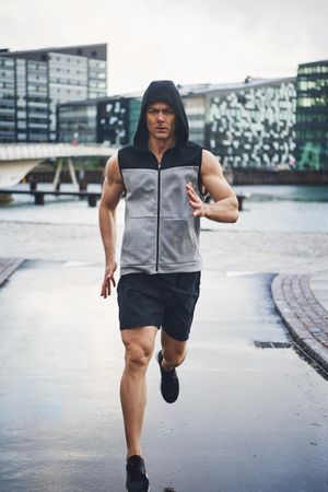 Intense muscular man in rain running in the rain